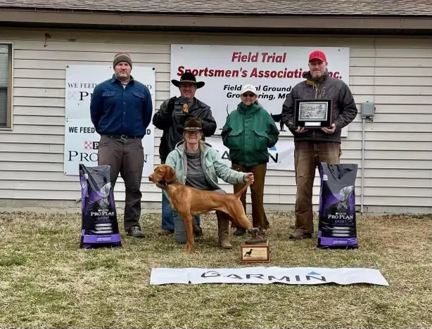 five people in hats with a brown dog